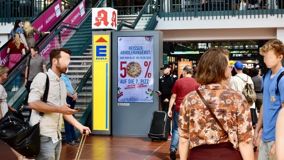 Domino's Kampagnenmotiv auf einem digitalen Screen im Bahnhofsumfeld